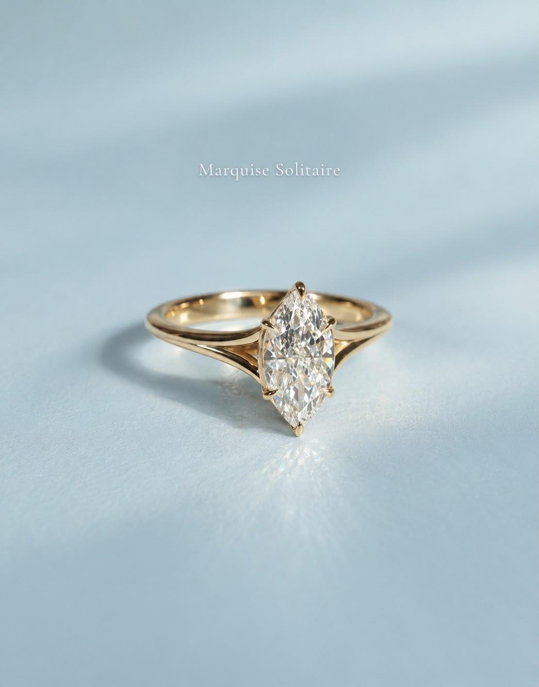 Yellow gold 1ct marquise solitaire with split shank on a pale ice-blue surface