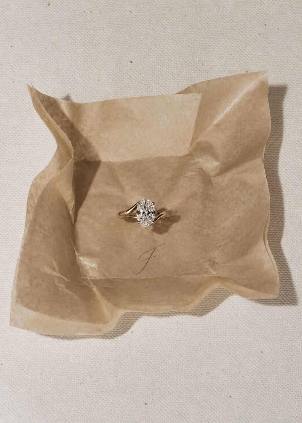 The Oval bypass solitaire on crumpled parchment tissue printed with a gold F