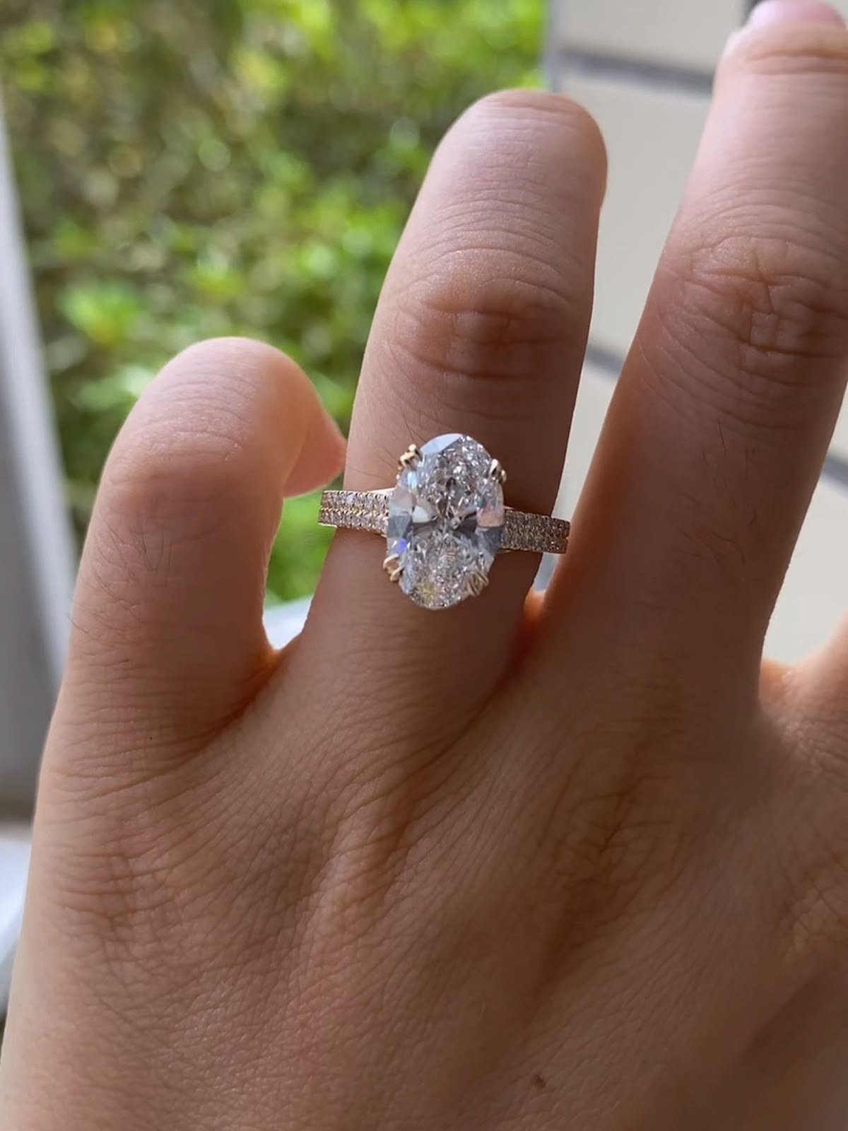 DRITË oval diamond ring worn on a hand held up to a window