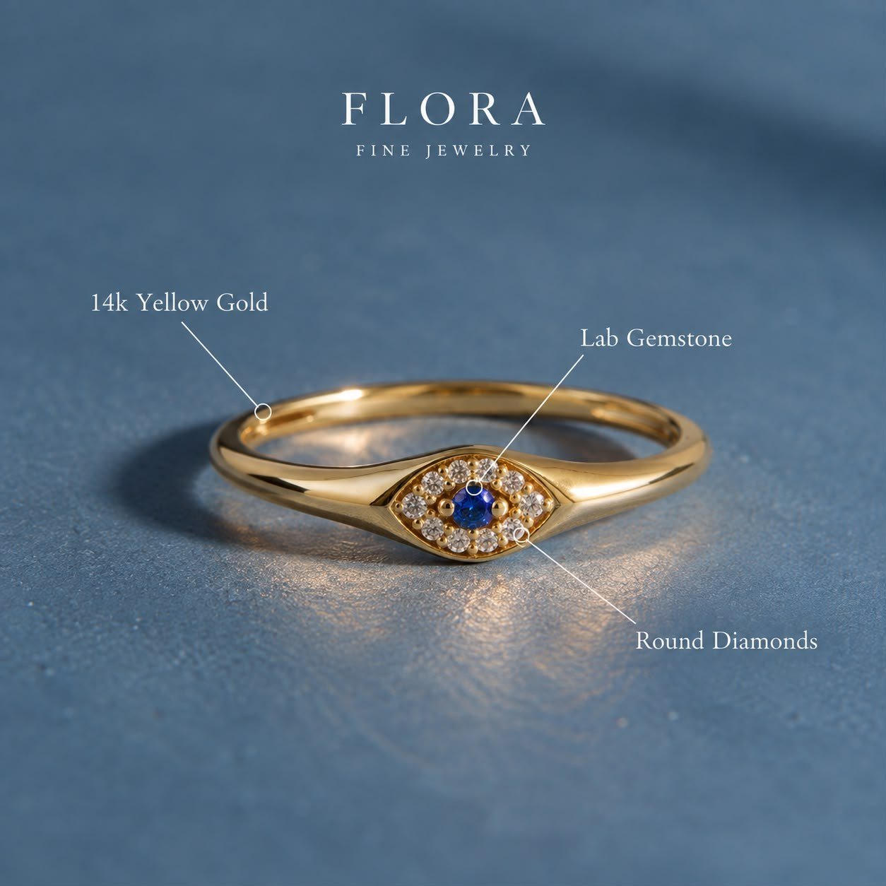 FLORA Evil Eye ring in 14K yellow gold, a blue lab-grown gemstone ringed with round diamonds, on blue