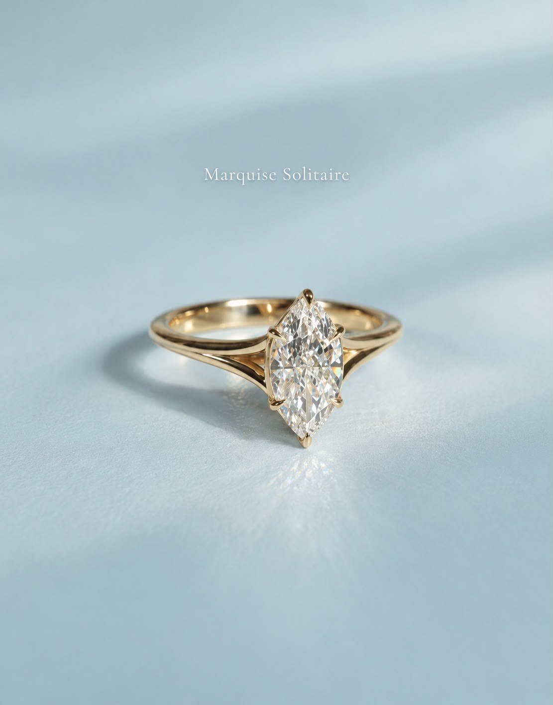 Yellow gold 1ct marquise solitaire with split shank on a pale ice-blue surface