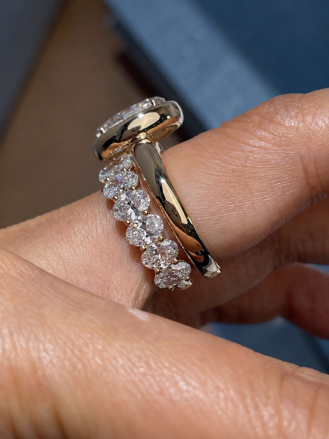 Side view of the bezel ring and eternity band stacked on a finger