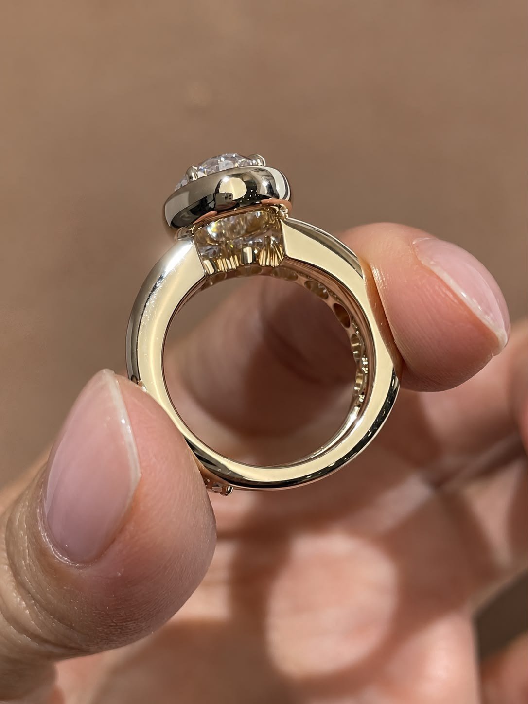 Underside of the bezel ring held up to the light, showing the gallery beneath the diamond