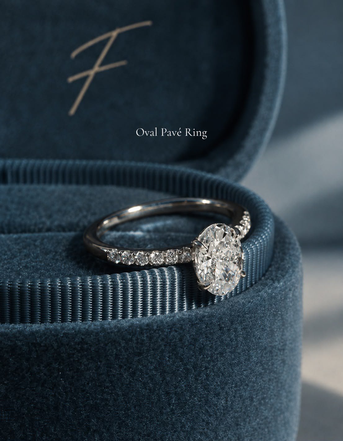 Oval Pavé Ring in 14k white gold resting on the rim of a petrol-blue velvet FLORA box