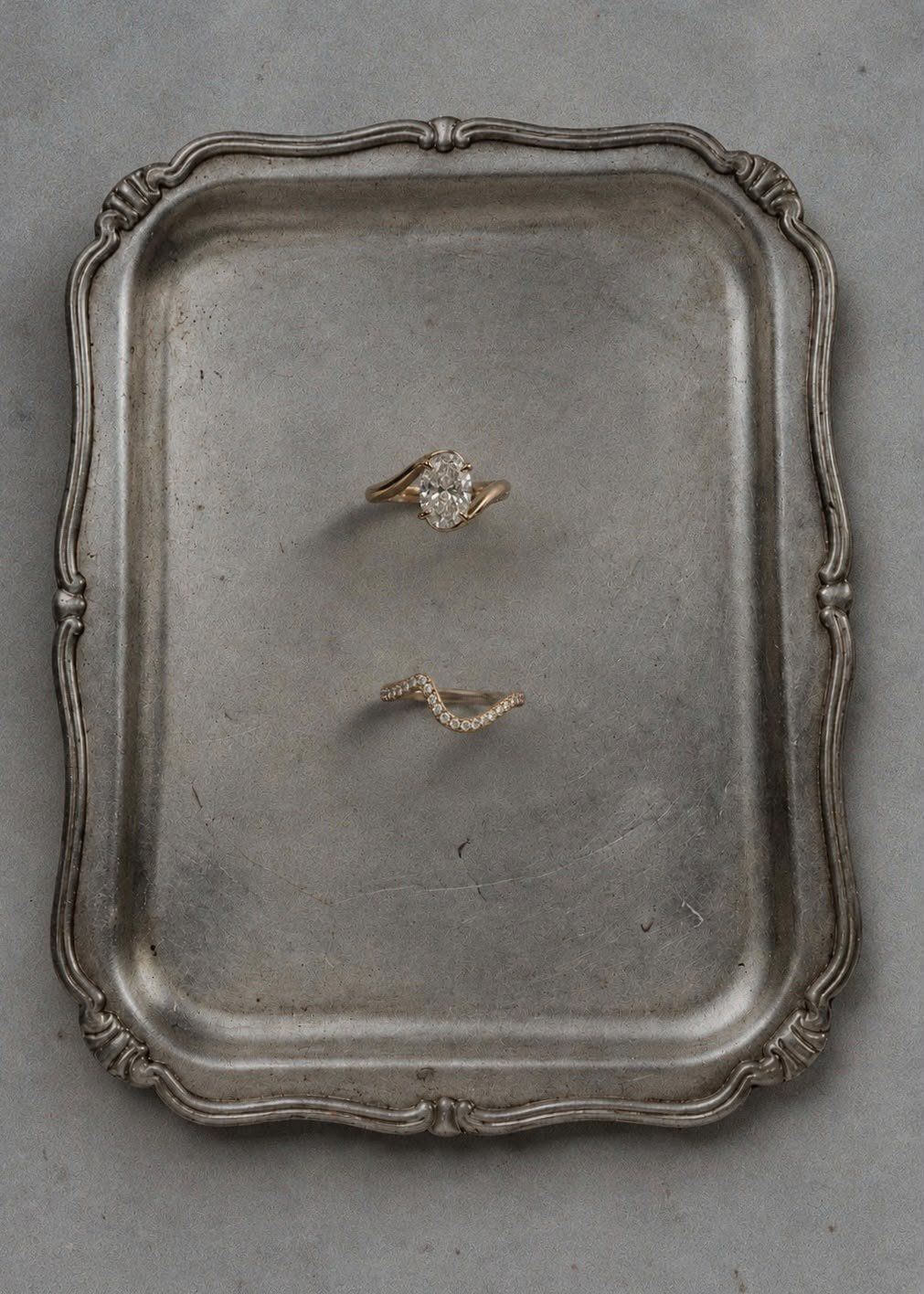 The Oval and curved pavé band on a pewter tray, in a cooler light